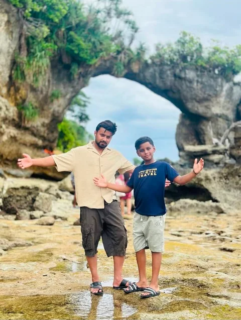 A guest and child visiting a natural coastal rock formation in the Andaman Islands