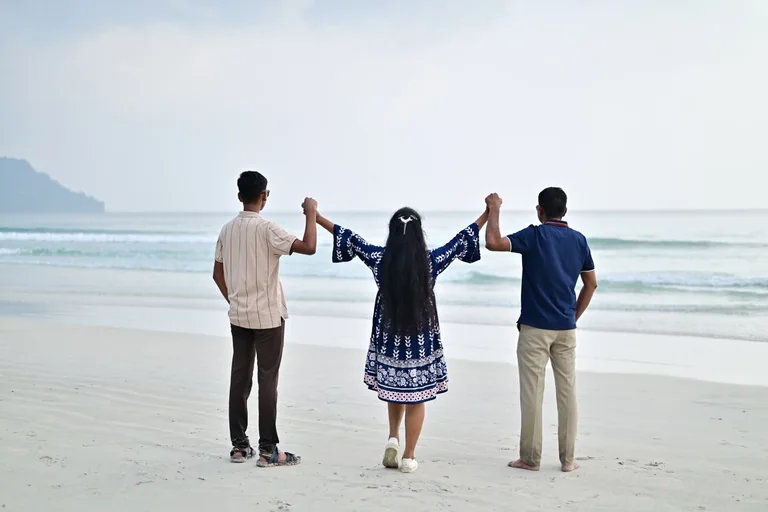 A family group walking together beside the Andaman Sea