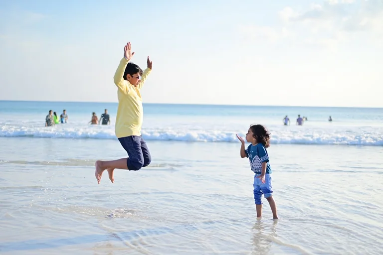 A guest and child playing together in the shallow sea