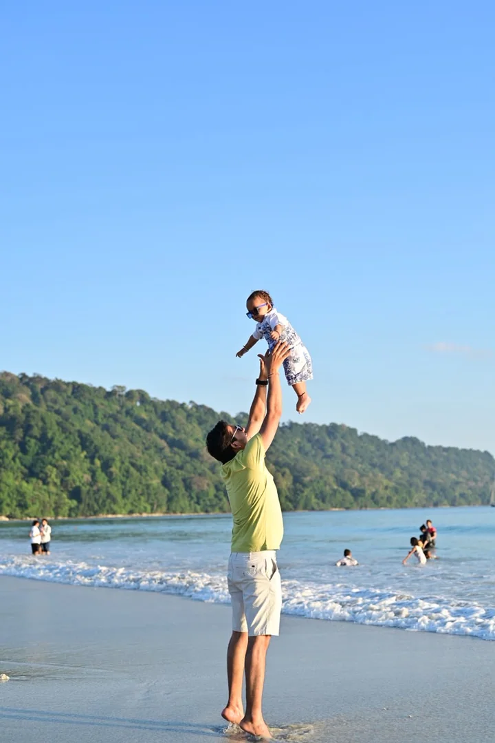 A guest lifting a child during a happy Andaman beach moment