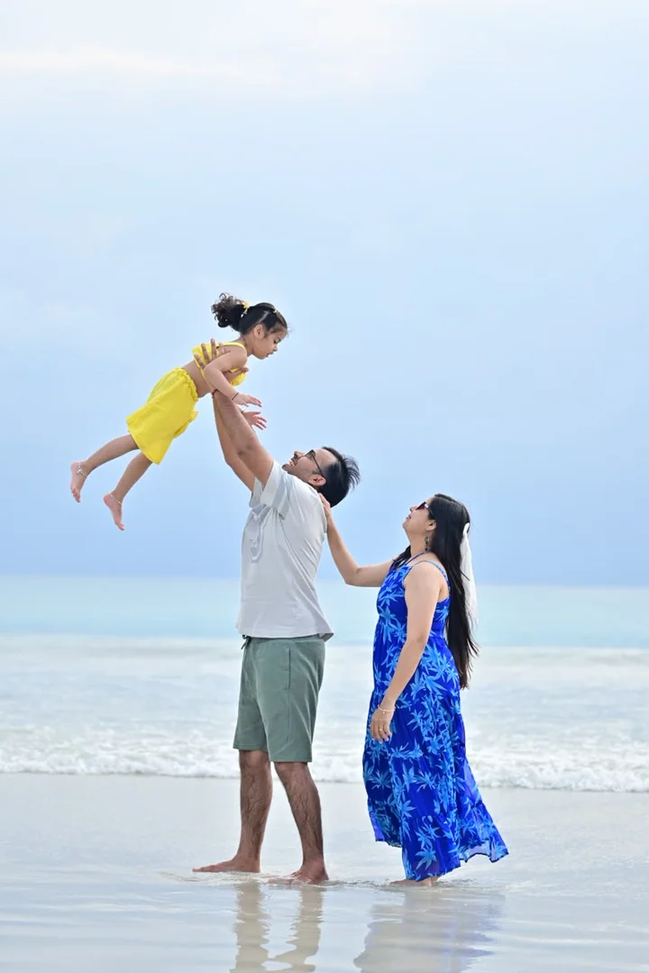 Parents lifting their child during a playful beach moment